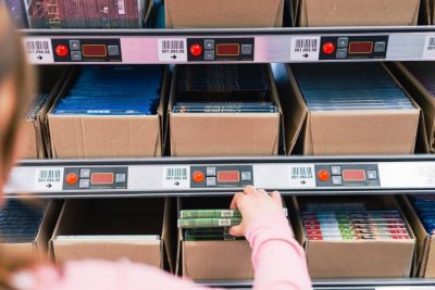 Mitarbeiterin von optimal media am Pick by light System zur tagesaktuelle Auftragsabwicklung und Versand von CDs, DVDs, Vinyl und Blu-Ray Discs