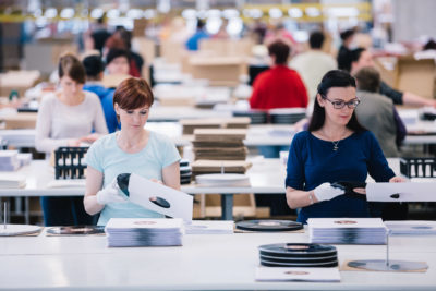 Mitarbeiter im Fulfillment Center von optimal media bei der Handverpackung von Schallplatten