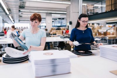 Mitarbeiter bei der Konfektionierung von Schallplaten im Schallplaten Presswerk in Röbel von optimal media