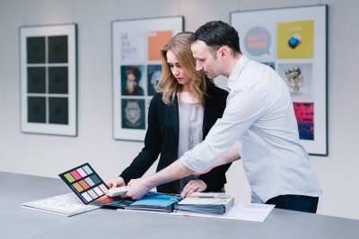 Beratungsgespräch bei optimal media Berater klärt Kunden über Farben und Papier der Druckerei und Buchbinderei auf